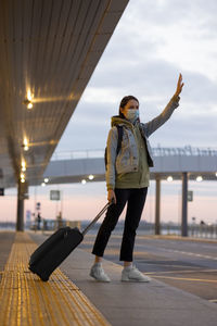 Full length of woman standing on illuminated road against sky