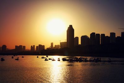 Scenic view of sea by buildings against sky during sunset