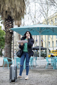 Full length of woman standing on seat against trees