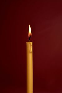 Close-up of lit candle in darkroom