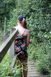 Rear view of woman standing by railing against trees