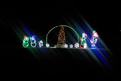 Illuminated ferris wheel against black background