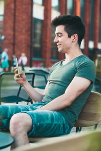 Side view of young man using mobile phone