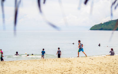 People playing on beach against sky