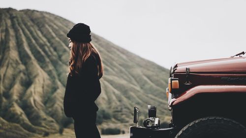 Rear view of woman standing on mountain against clear sky