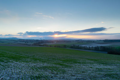 Scenic view of agricultural field against sky during sunset