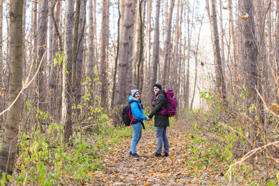 Rear view of people standing in forest