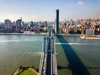 High angle view of manhattan bridge over river by buildings against sky