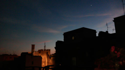 Silhouette houses against sky at night
