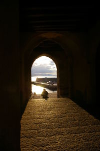 Silhouette of building by sea against sky