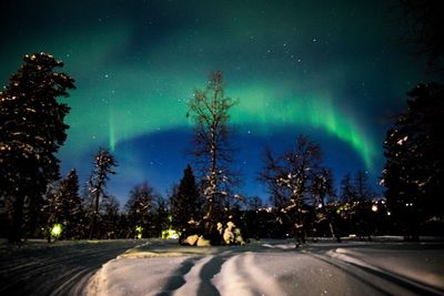 Road passing through snow covered landscape at night