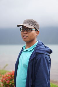 Portrait of smiling young man standing against sky