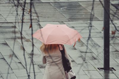 Rear view of woman holding umbrella on footpath