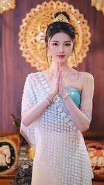 Portrait of young woman standing against wall