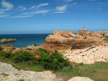 Rock formations by sea against blue sky