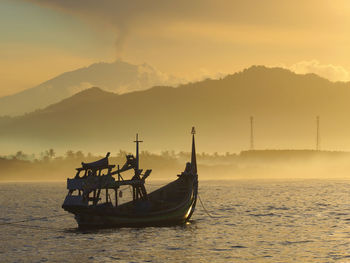 Silhouette ship in sea against sky during sunset