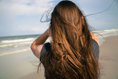 Rear view of woman with long brown hair on beach