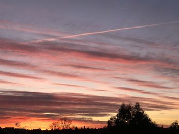 Low angle view of silhouette trees against dramatic sky