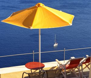 Chairs and table by sea against sky