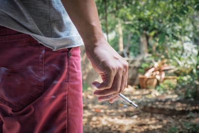 Midsection of man holding cigarette