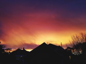 Silhouette houses against sky during sunset