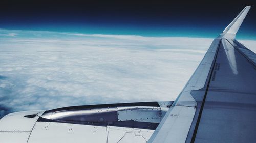 Cropped image of airplane wing over clouds