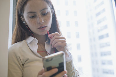 Young woman talking on smartphone through headphone