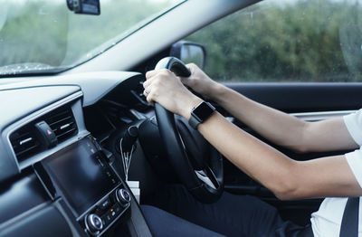 Midsection of woman holding umbrella in car