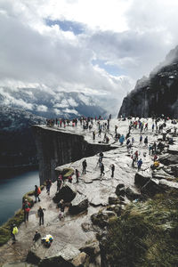 High angle view of people on mountain against cloudy sky during winter