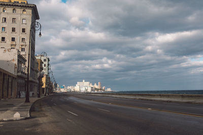 Road by buildings against sky in city