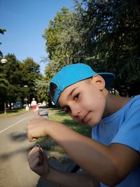 Portrait of boy gesturing thumbs up while standing against trees