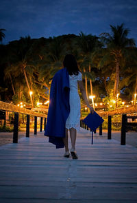 Rear view of women walking on footbridge at night