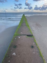 Surface level of footpath by sea against sky