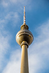 Low angle view of communications tower against cloudy sky