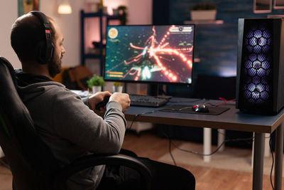 Rear view of man using laptop at home