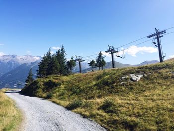 Scenic view of road by mountains against clear blue sky