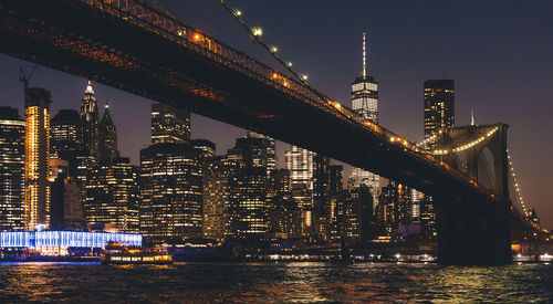 Illuminated city buildings by river at night