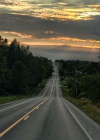 Road amidst trees against sky during sunset