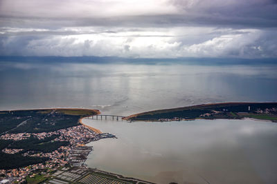 Aerial view of city by sea against sky