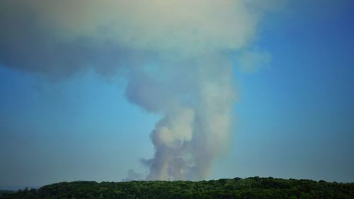 Smoke emitting from volcanic mountain against blue sky