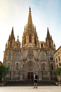 Rear view of skateboarder at barcelona cathedral against sky