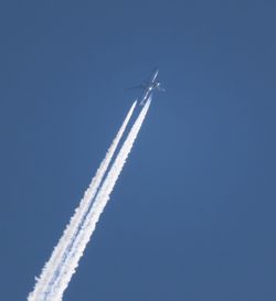 Low angle view of airplane flying against blue sky