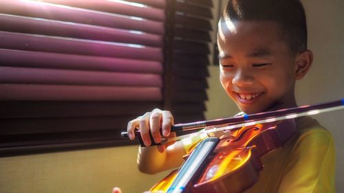 Smiling boy playing violin at home