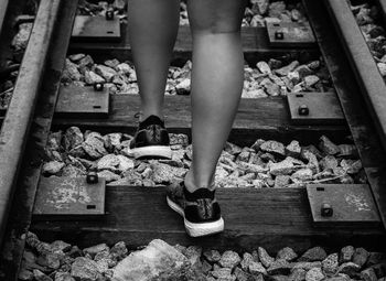 Low section of woman standing on railroad track