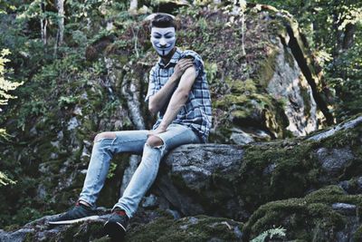 Full length of man sitting on rock