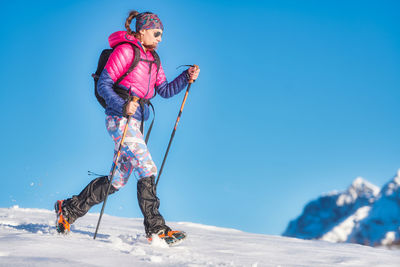 Full length of woman on snow against clear blue sky