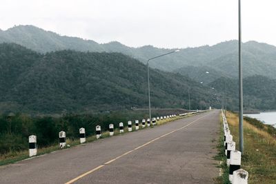 Road by mountains against sky