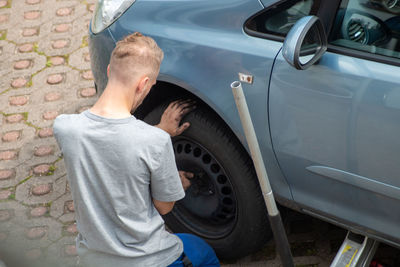 Rear view of man repairing car 