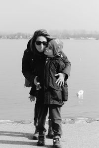 Mother and son standing against river