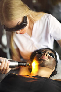 Beautician treating woman with laser in clinic